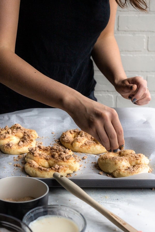 adding the topping to cinnamon crunch soft pretzels before baking