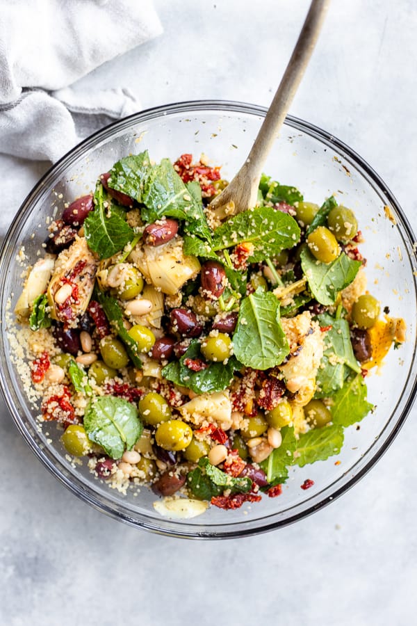a bowl of antipasto couscous salad with a spoon