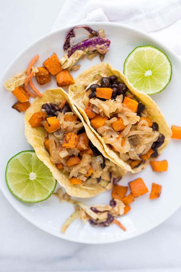 Fall Butternut Squash Tacos: These gluten free and vegan tacos are filled with ingredients like roasted squash, seasoned black beans, hummus slaw, and caramelized onions! An easy and healthy way to enjoy tacos this season! || fooduzzi.com recipe