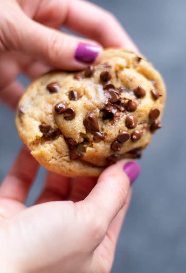 Two hands splitting a Chewy Vegan Peanut Butter Cup Cookie in half