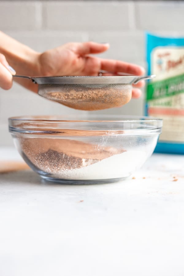sifting cocoa powder into a glass bowl