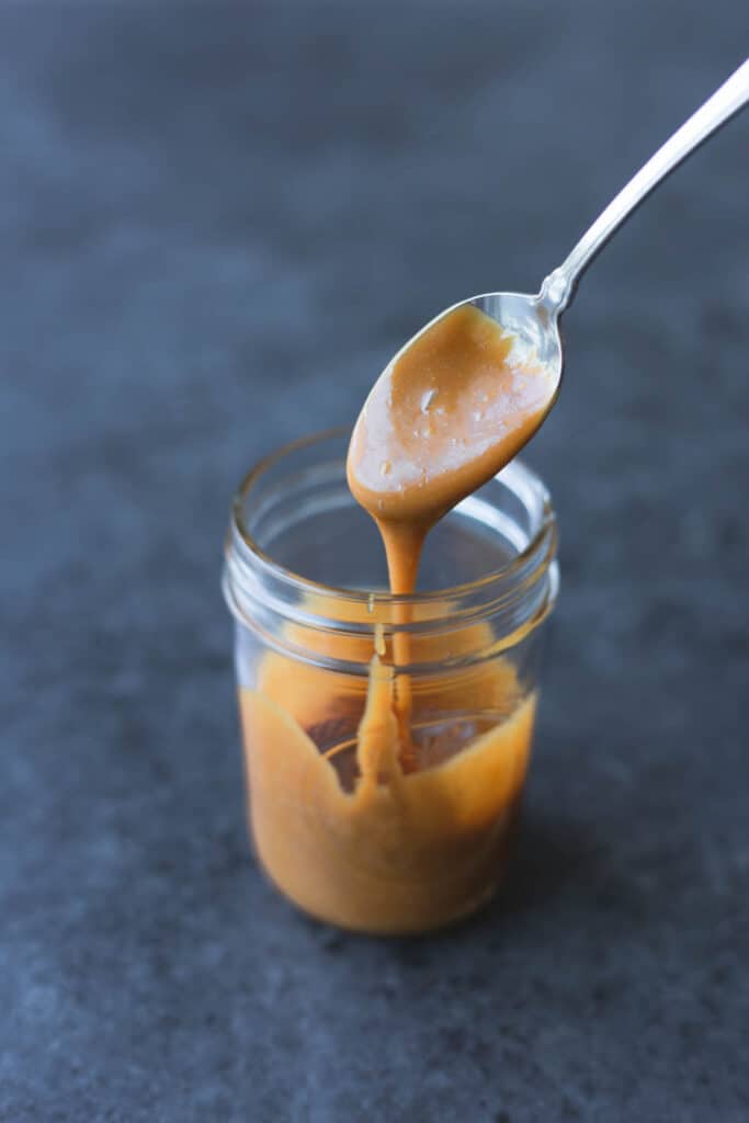 a spoon drizzling cookie butter syrup out of a mason jar