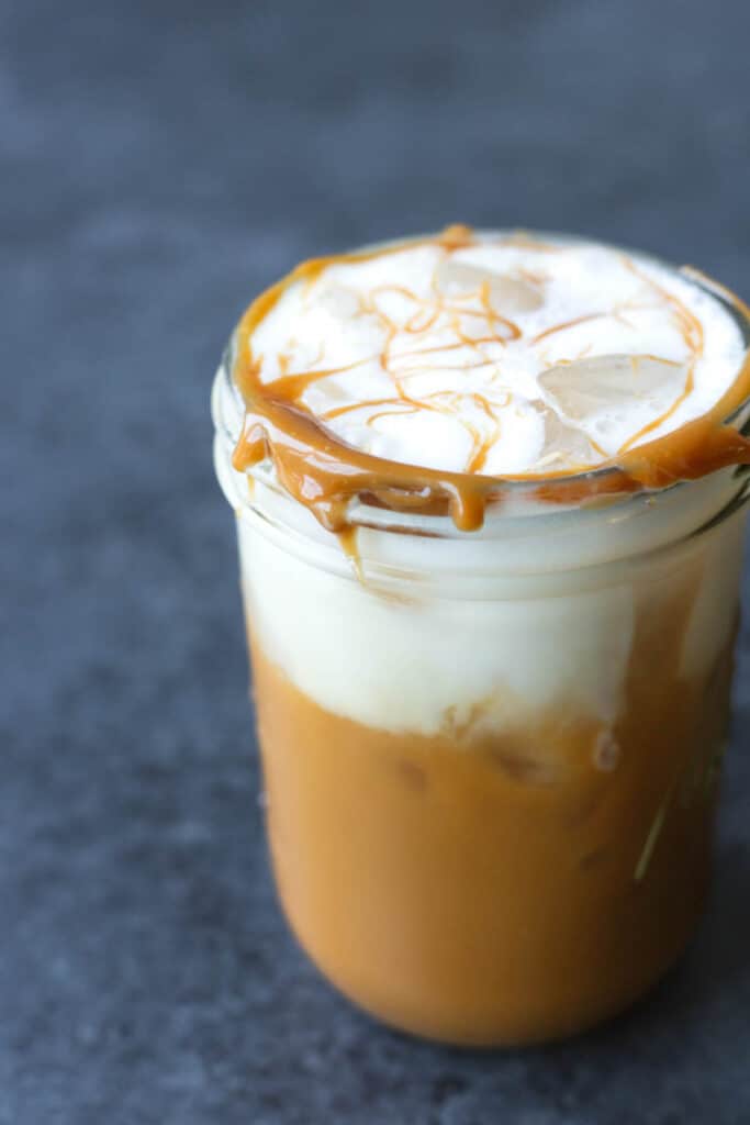 a cookie butter iced coffee with vanilla oatmilk cold foam in a mason jar