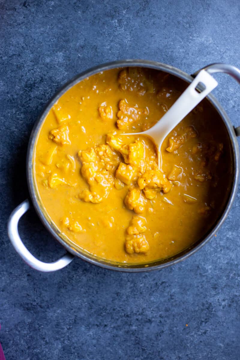 a pot of potato cauliflower curry with a spoon sticking out of it