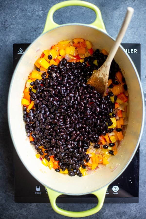 an oval dutch oven with peppers and black beans in it