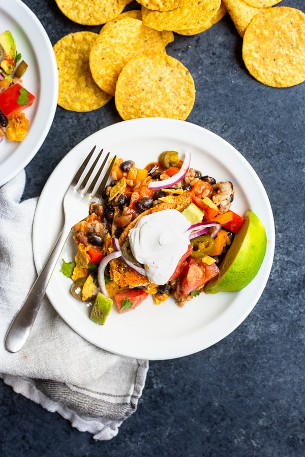 a plate of the one-pot vegan enchilada casserole with sour cream and a lime wedge