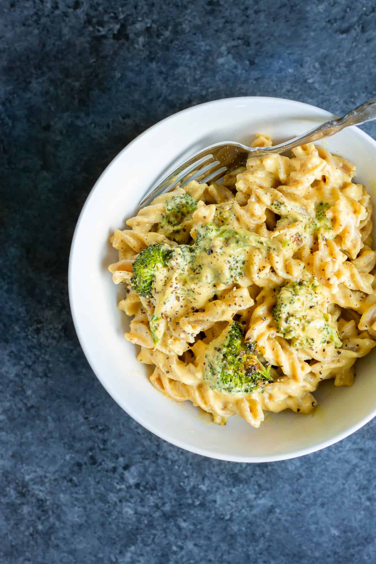 a bowl full of pasta, roasted broccoli, and instant pot vegan cheese sauce