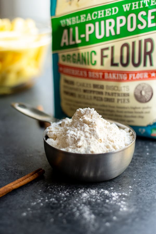 a measuring cup of flour with cinnamon sticks and a bag of Bob's Red Mill Organic All-Purpose Flour