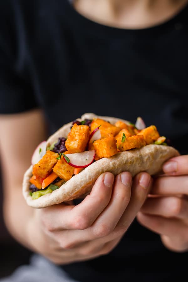 girl holding a vegan buffalo tofu taco