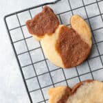 a tri-colored cookie in the shape of a cat on a black cooling rack