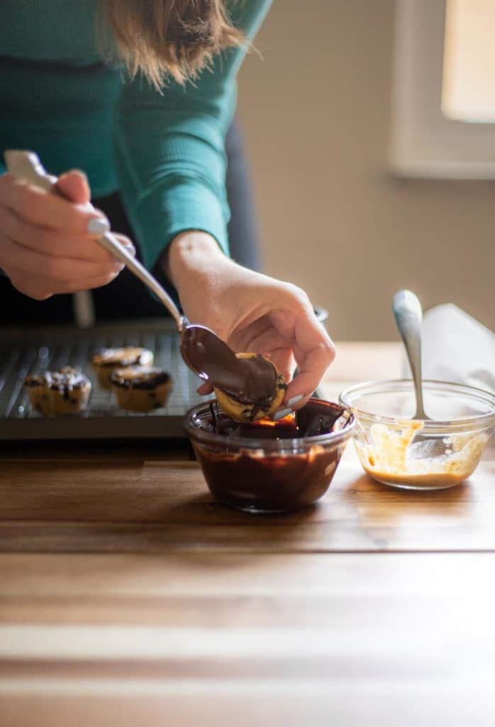 hand scooping melted chocolate onto a vegan chocolate peanut butter cookie dough bite