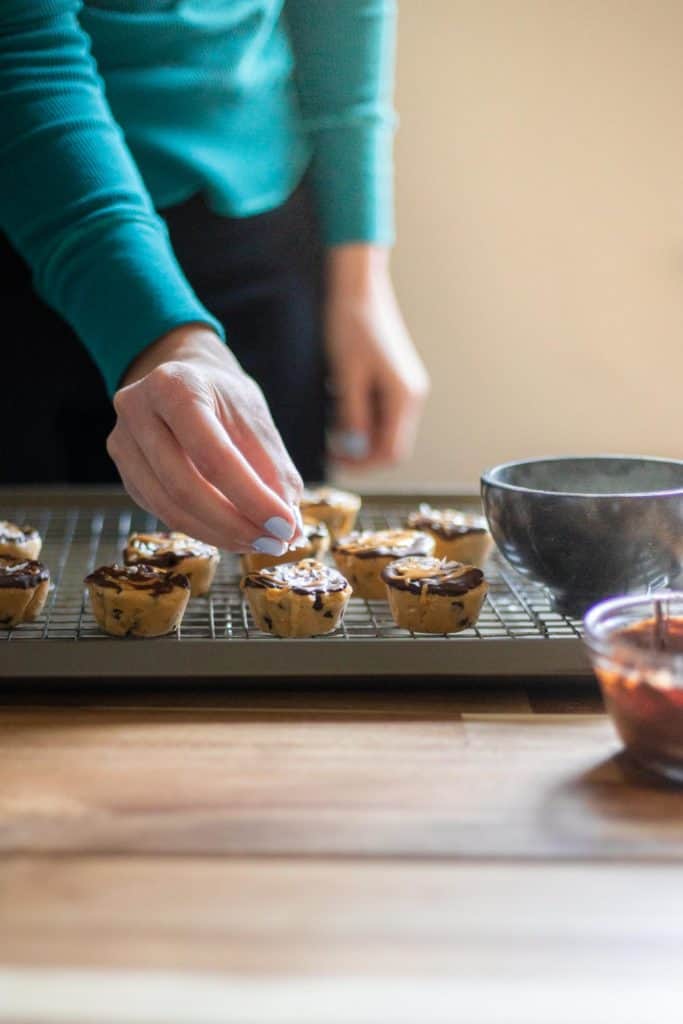 hand sprinkling flaky salt on a vegan cookie dough bite