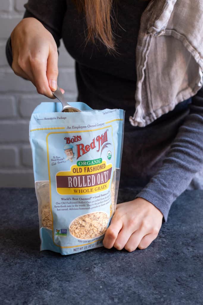 a girl scooping oats from a bag of Bob's Red Mill Organic Rolled Oats