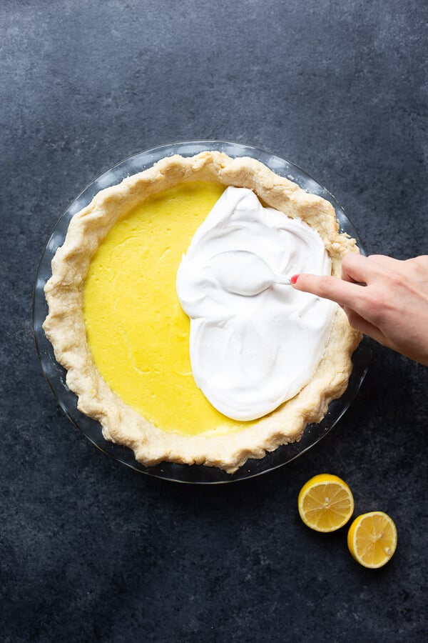 spooning meringue on a vegan lemon meringue pie