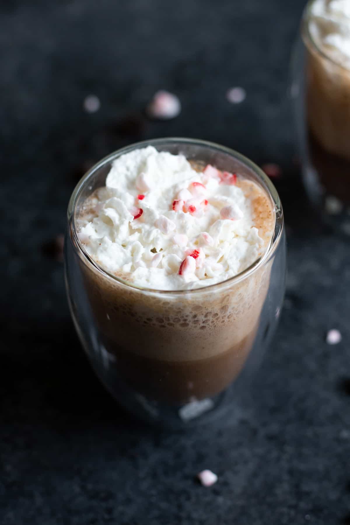 a vegan oat milk peppermint mocha latte in a glass cup with whipped cream on top