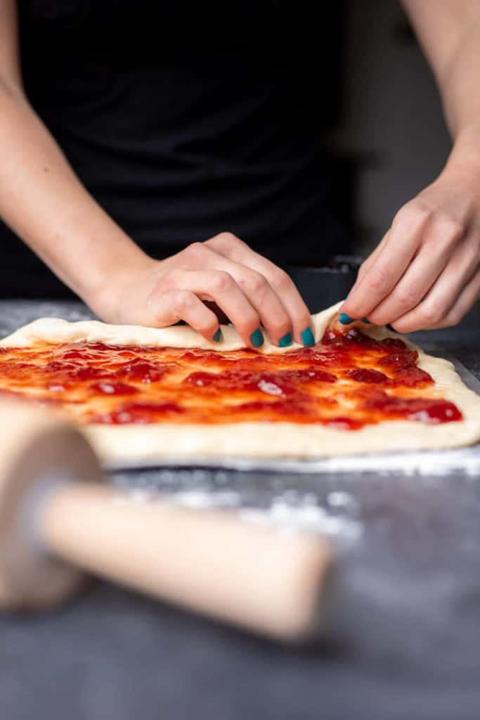 Hands rolling up Vegan Strawberry Lemon Sweet Rolls