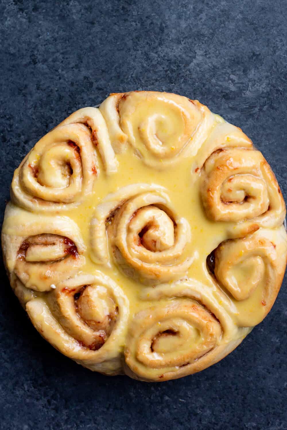Baked and glazed vegan strawberry lemon sweet rolls on a dark background