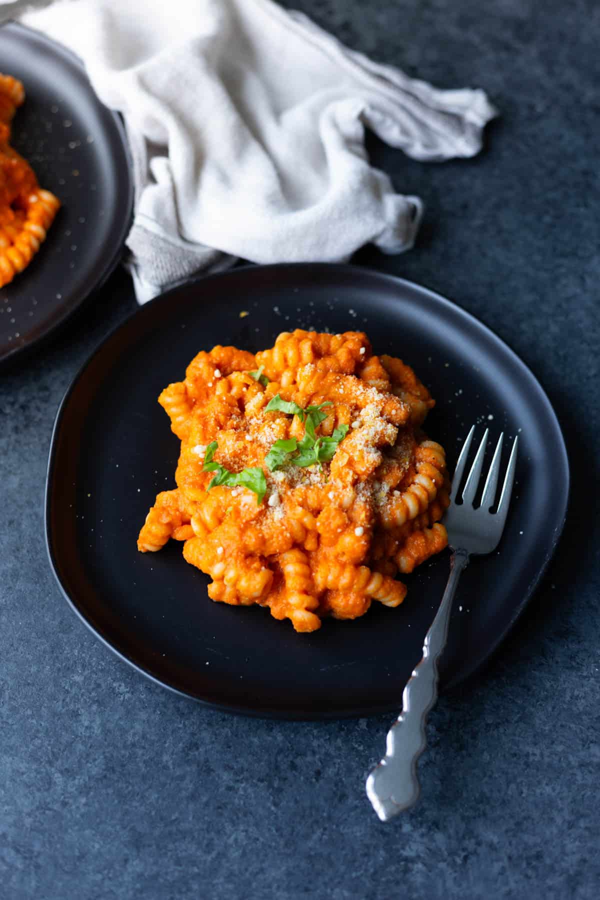 vegan vodka sauce pasta on a black plate with a fork